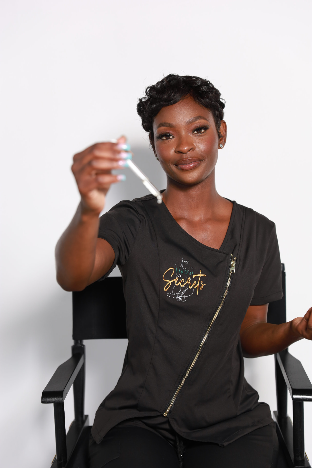 Founder and esthetician of Skin Out Secrets holding a dropper of body oil